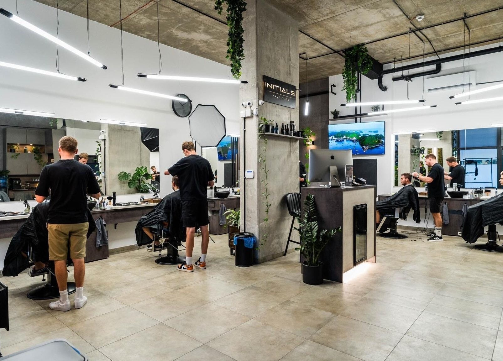 Modern salon with clients getting styled at Initials, Budapest, Magyar, HU. Bright, trendy interior with lush plants.