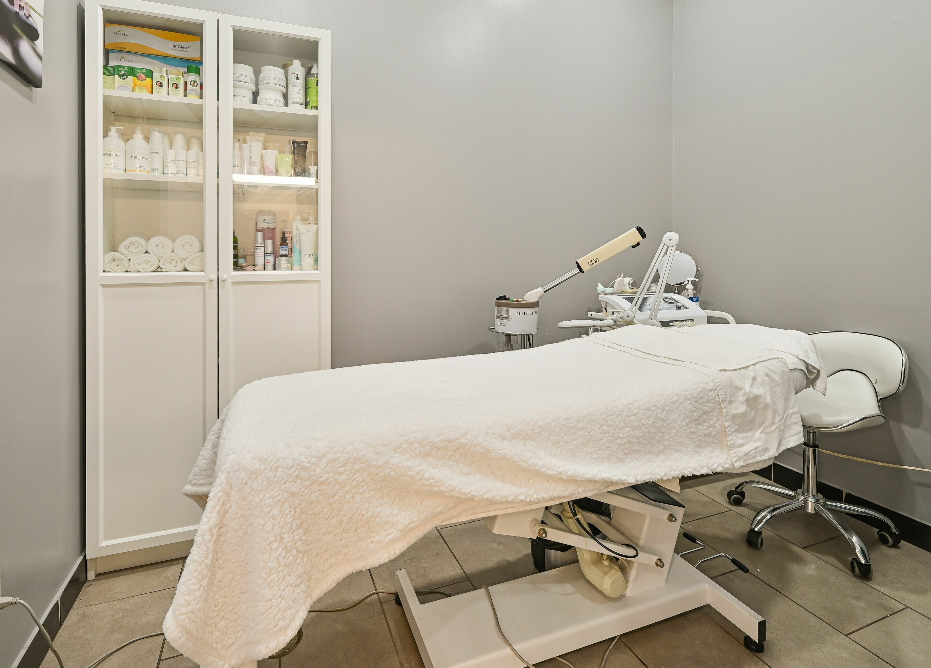 Tranquil treatment room at VU Salon and Spa, Mississauga, Ontario, CA, featuring a treatment bed and skincare products.