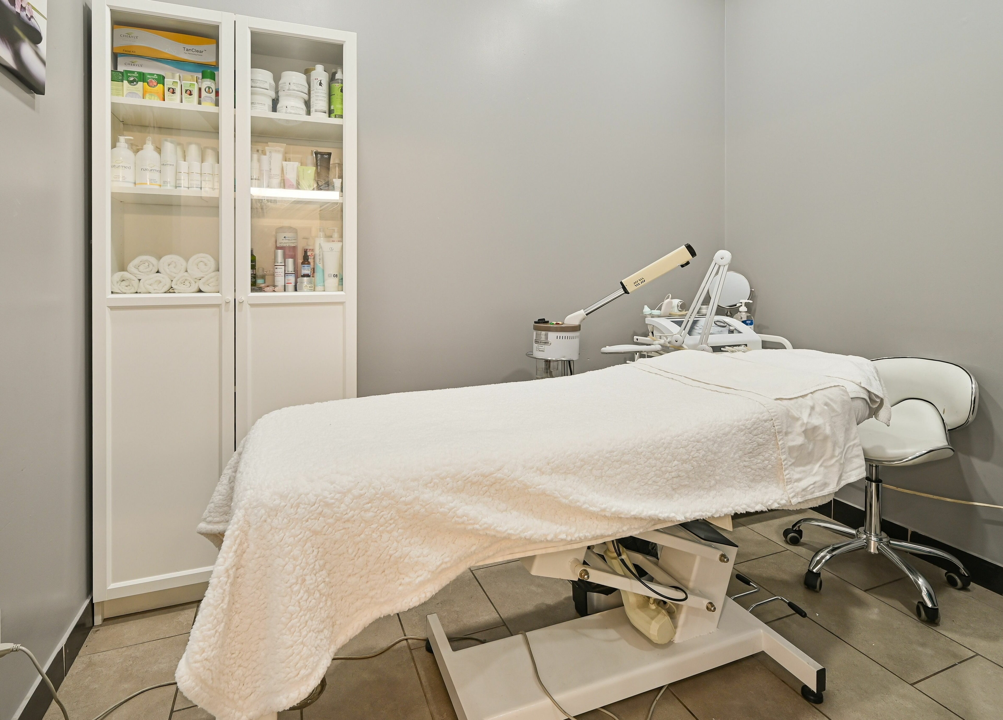 Tranquil treatment room at VU Salon and Spa, Mississauga, Ontario, CA, featuring a treatment bed and skincare products.