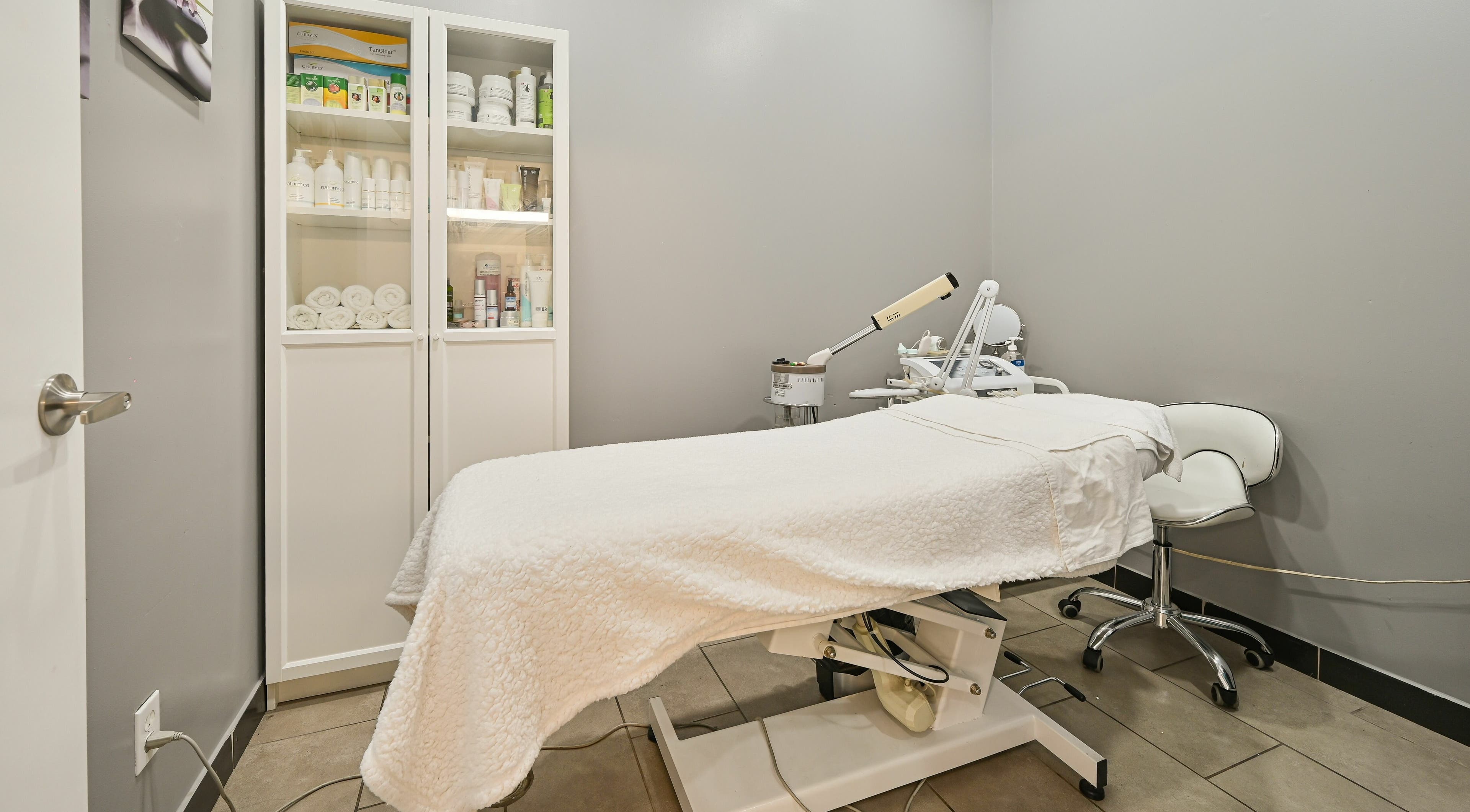 Tranquil treatment room at VU Salon and Spa, Mississauga, Ontario, CA, featuring a treatment bed and skincare products.