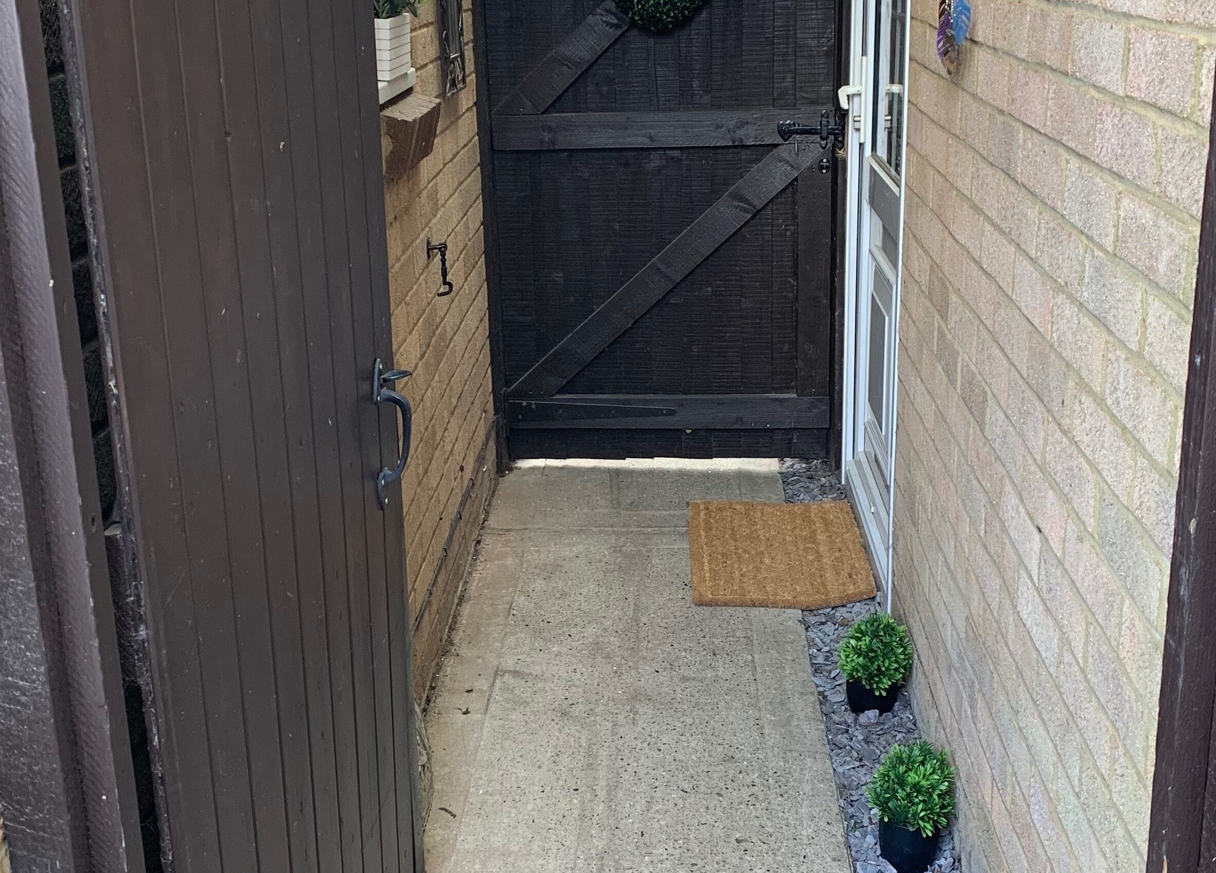 Welcoming entrance of Holistic Therapy by Kayleigh in Baldock, England, GB, with wooden gate and potted plants.
