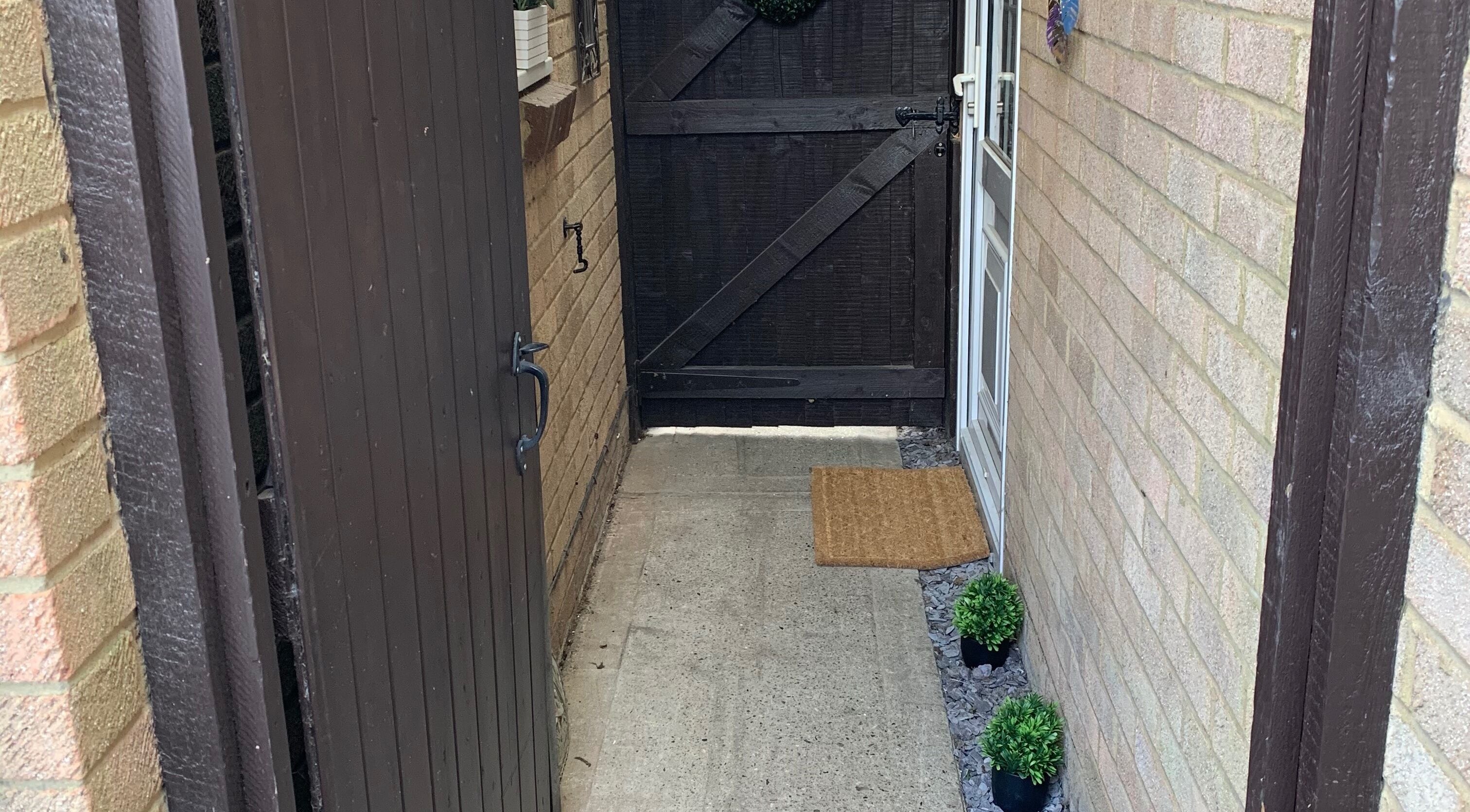 Welcoming entrance of Holistic Therapy by Kayleigh in Baldock, England, GB, with wooden gate and potted plants.
