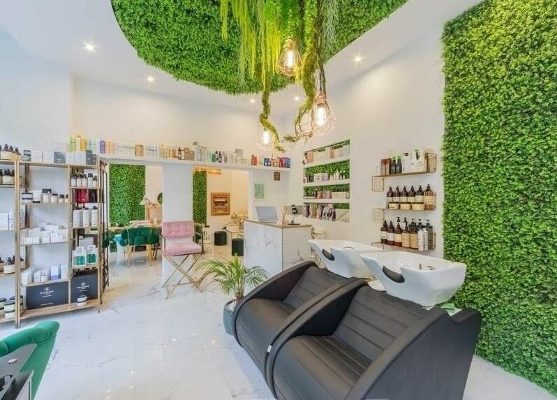 Interior modern al 4AM Beauty and Shop, București, cu design verde luxuriant și produse pe afișaj.