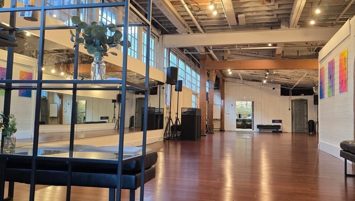 Spacious dance studio at PIVOT Dance Emporium in Seattle, Washington, US with wooden floors and large windows.