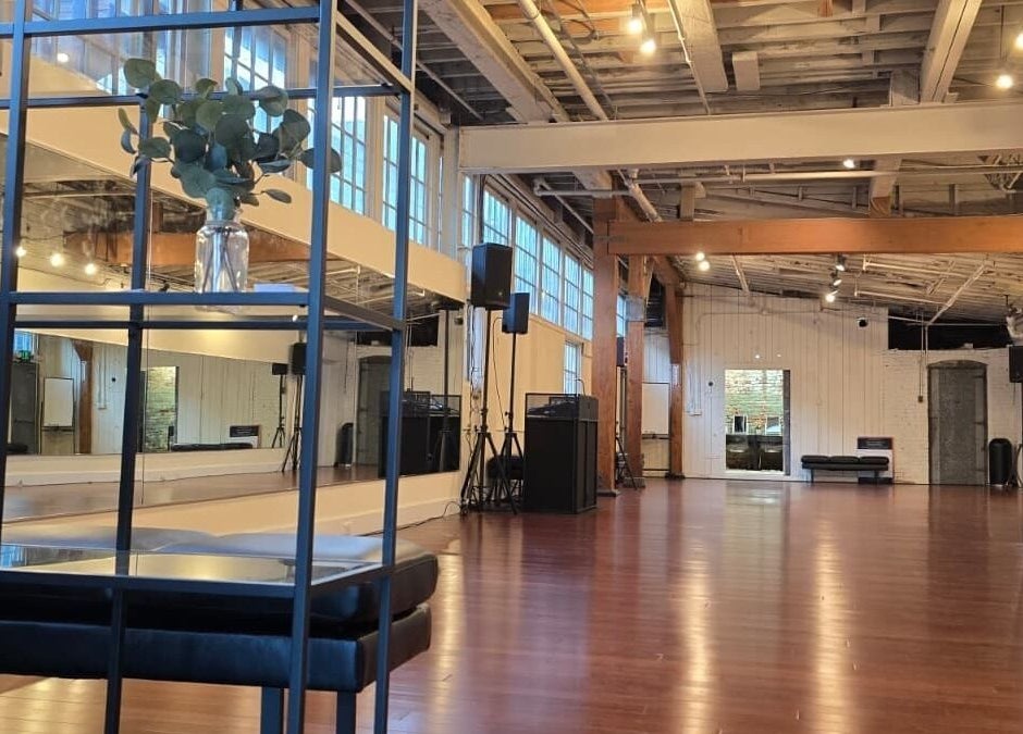 Spacious dance studio at PIVOT Dance Emporium in Seattle, Washington, US with wooden floors and large windows.