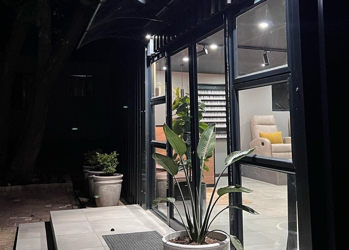 Entrance of Giggles n Kurls Nail Studio Hartbeespoort, showcasing bright interior and lush potted plants, Hartbeespoort, North West, ZA.