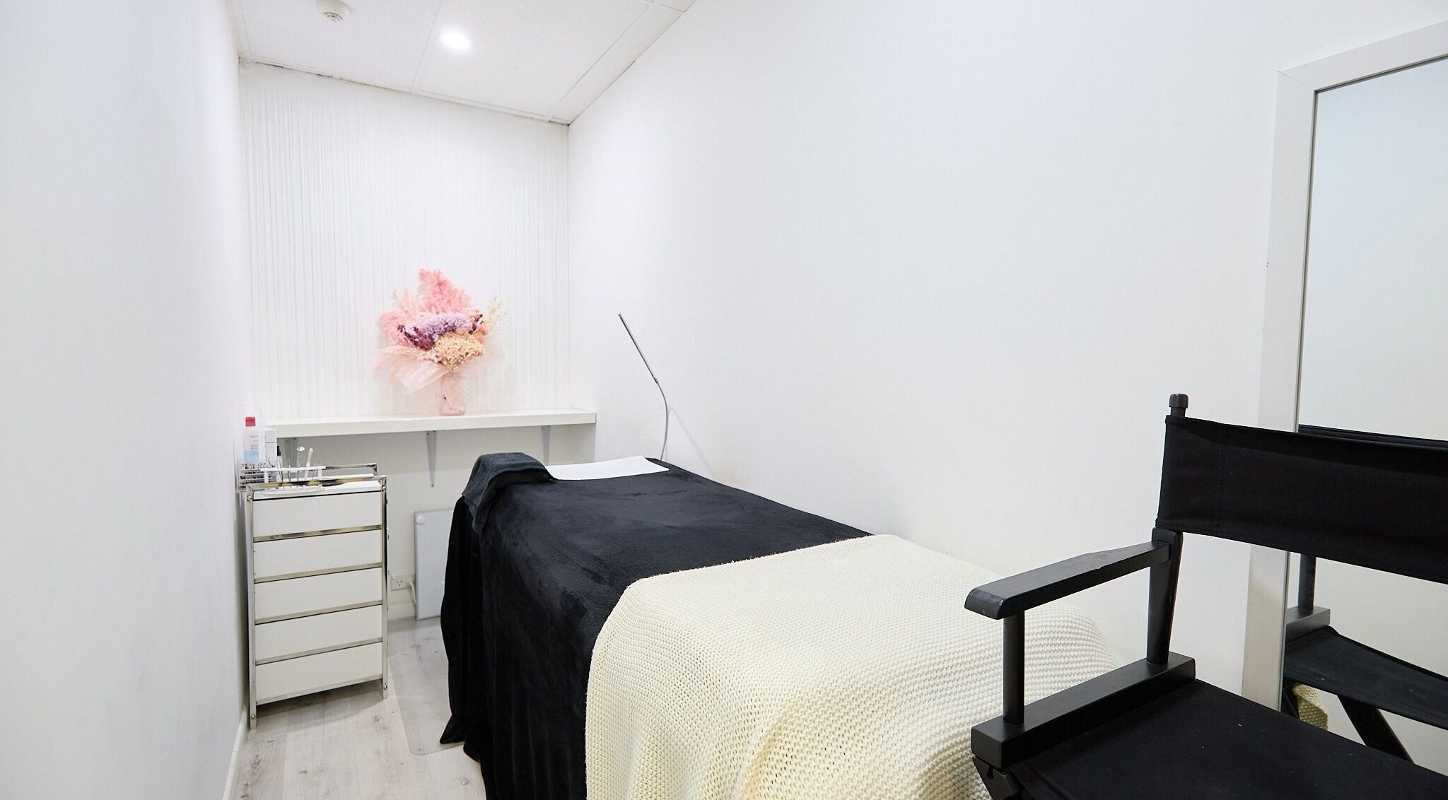 Lash Bar's tranquil treatment room in Bondi Junction, New South Wales, AU, featuring a cozy bed and elegant decor.