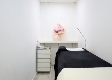 A tranquil treatment room at Lash Bar, Bondi Junction, New South Wales, AU, featuring a black bed and floral decor.
