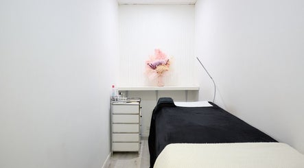 A tranquil treatment room at Lash Bar, Bondi Junction, New South Wales, AU, featuring a black bed and floral decor.