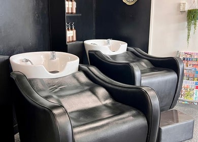 Luxurious wash stations at Blink Hair Design in Christchurch, Canterbury, NZ, featuring sleek black chairs and shampoo bottles.