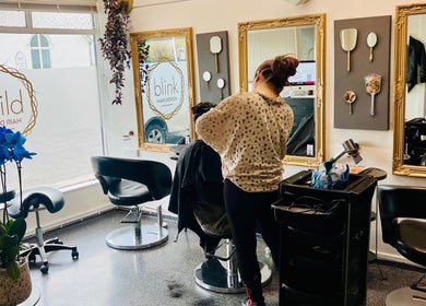 Interior of Blink Hair Design, Christchurch, Canterbury, NZ, showcasing stylist at work with elegant mirrors.