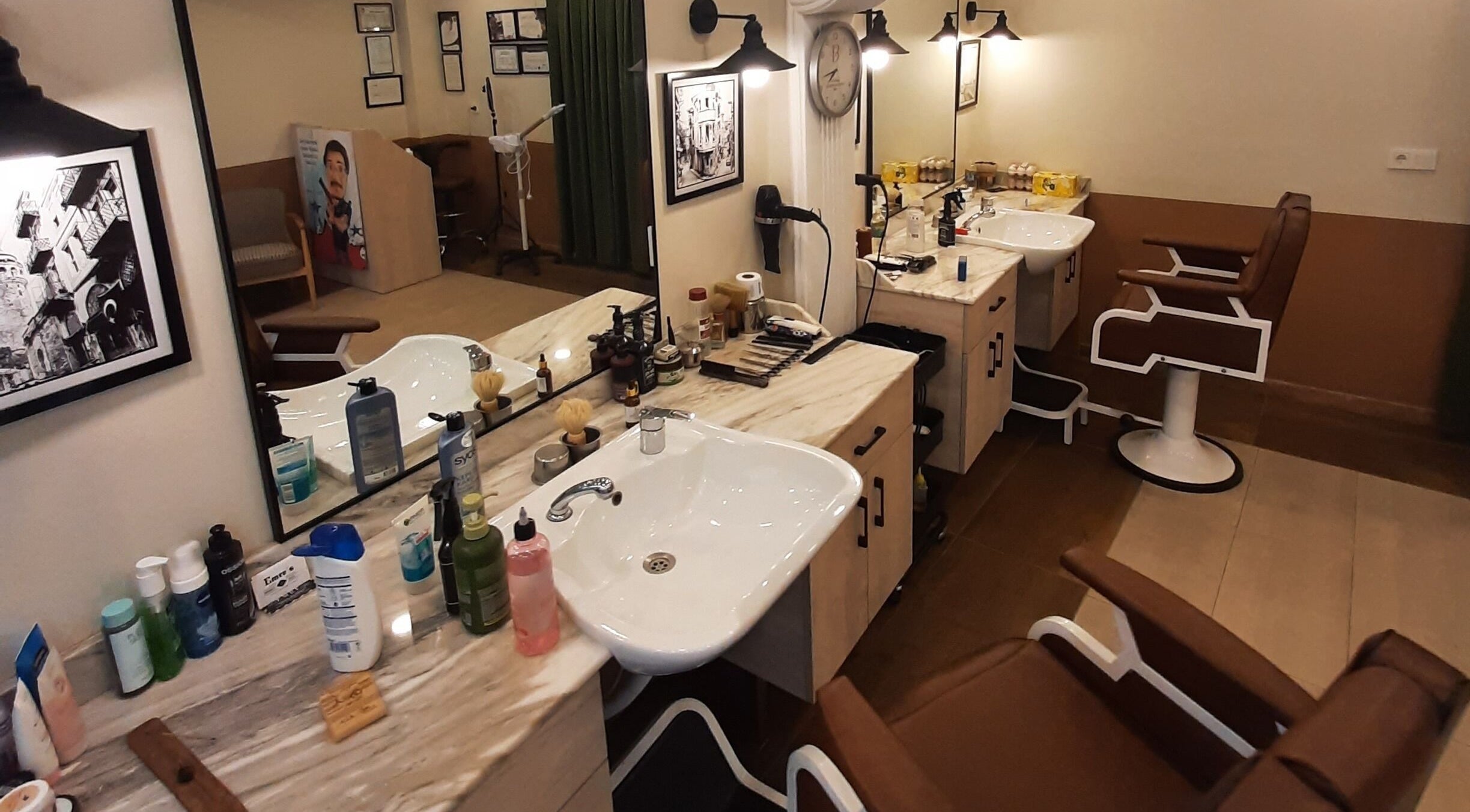Interior of Emre's Barbershop Dolapdere in İstanbul, İstanbul, TR with stylish barber chairs and grooming products.
