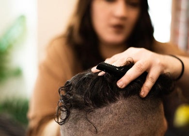 Stylist at Redcliff Refinery Barbershop & Salon in Redcliff, Alberta, CA gives a haircut.