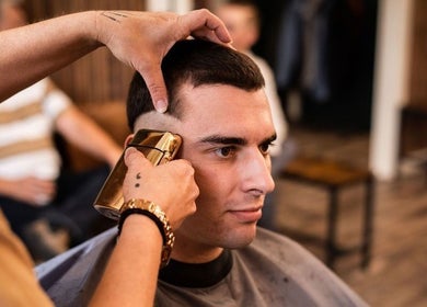 Barber carefully trims hair at Redcliff Refinery Barbershop & Salon in Redcliff, Alberta, CA.