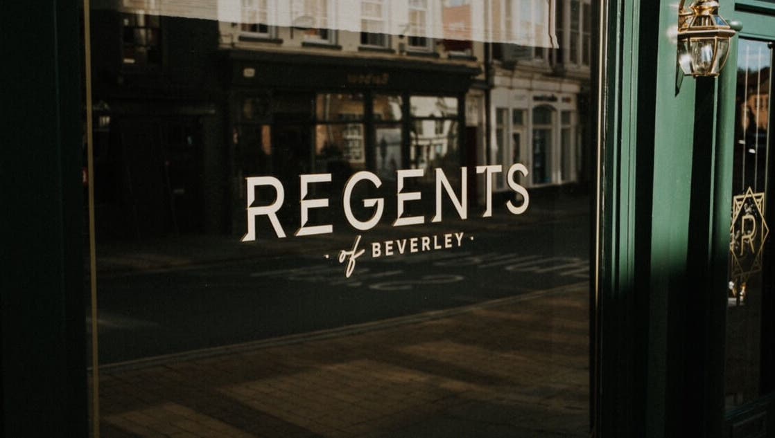 Elegant reflection of Regents of Beverley signage on a glass door in Beverley, England, GB.