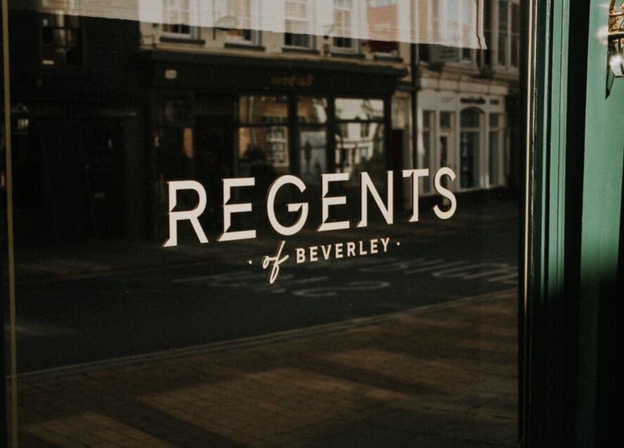 Elegant reflection of Regents of Beverley signage on a glass door in Beverley, England, GB.