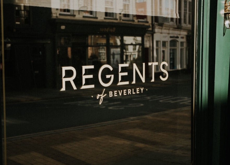 Elegant reflection of Regents of Beverley signage on a glass door in Beverley, England, GB.