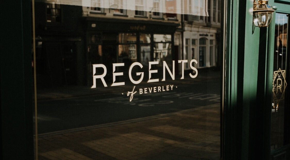 Elegant reflection of Regents of Beverley signage on a glass door in Beverley, England, GB.