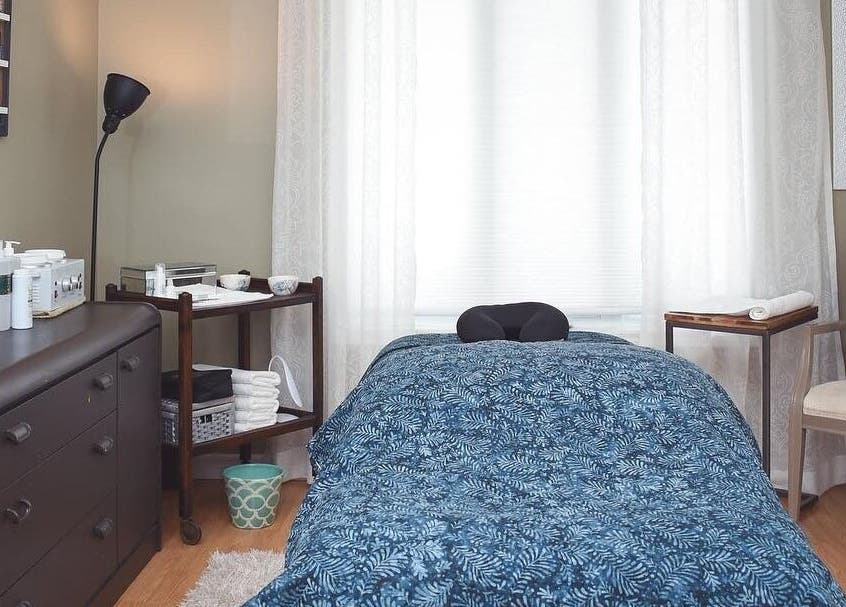 Cozy massage room at Bronzed Beauty Bar in Lucan, Ontario, CA featuring a tranquil setting with plush bedding.