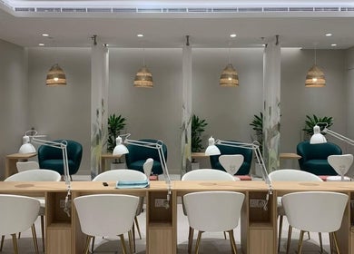 Modern nail salon interior at Home Service, دبي, دبي, AE. Elegant wooden desks, white chairs, hanging lights.