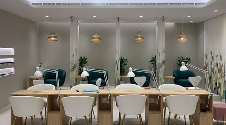 Modern nail salon interior at Home Service, دبي, دبي, AE. Elegant wooden desks, white chairs, hanging lights.