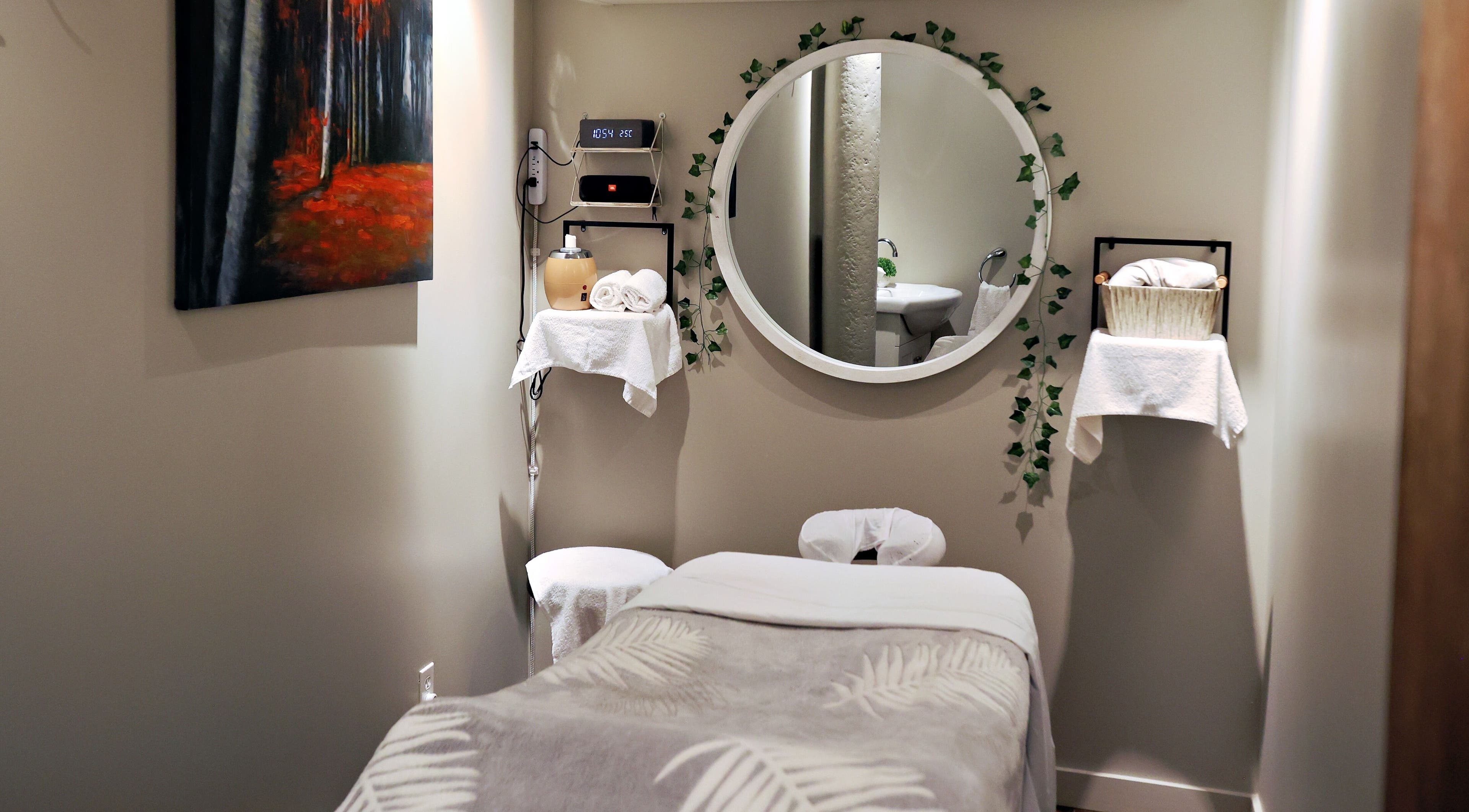 Salle de soin paisible à Aria Rituels du bien-être, Québec, Québec, CA, avec miroir rond et décor apaisant.