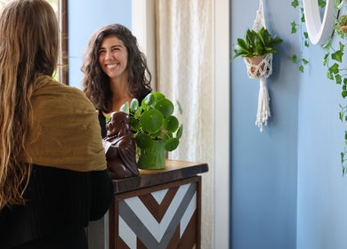 Réceptionniste souriante à Aria Rituels du bien-être, Québec, Québec, CA. Décor apaisant et plantes vertes.