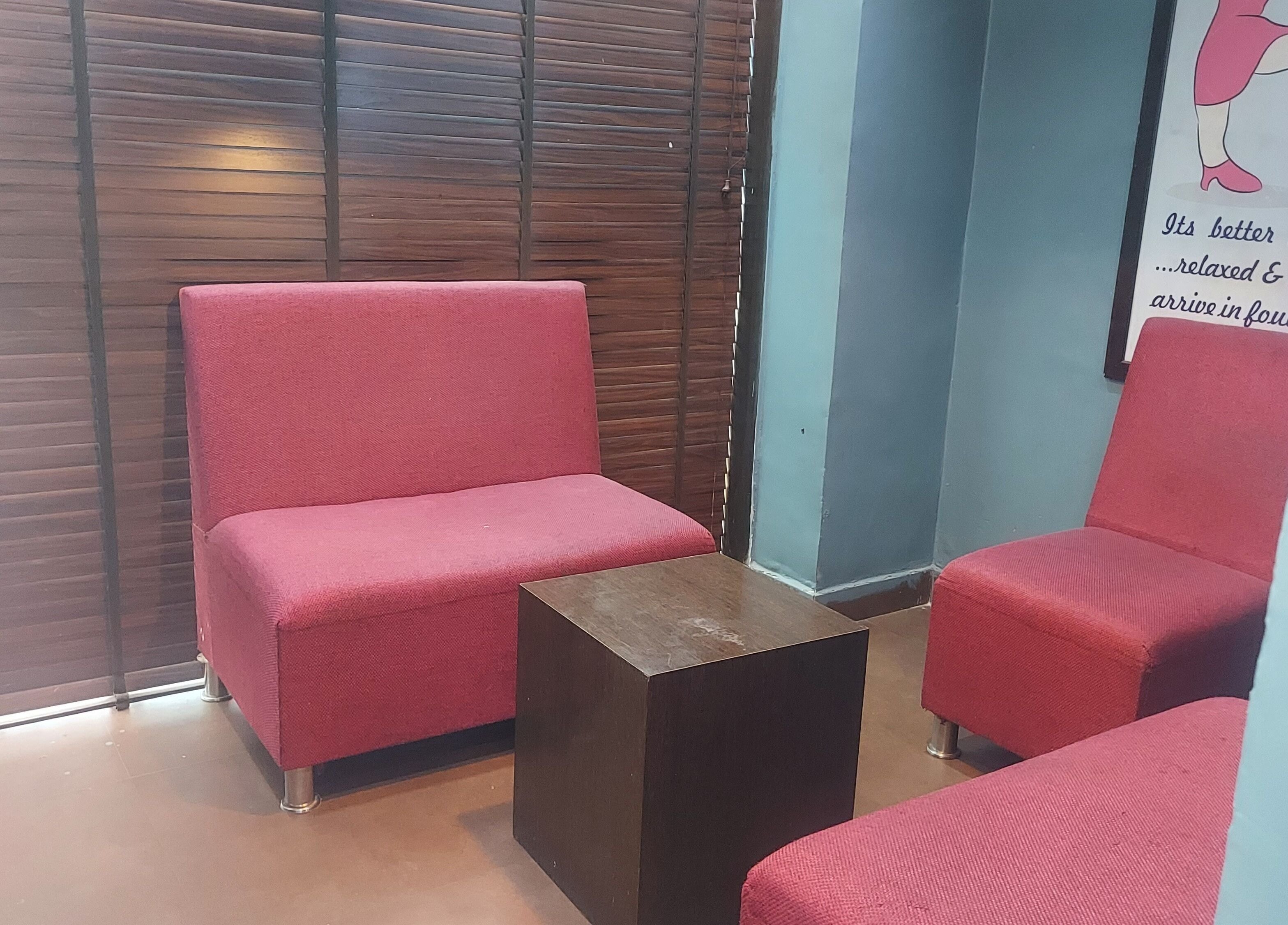 Comfortable seating area at Blue Tree Spa, Ghaziabad, Uttar Pradesh, IN with red chairs and wooden decor.