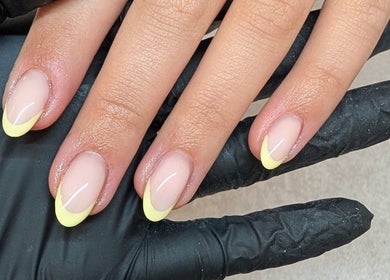 Elegant yellow-tipped nails on gloved hands at Amber Lees, Conwy, Wales, GB.