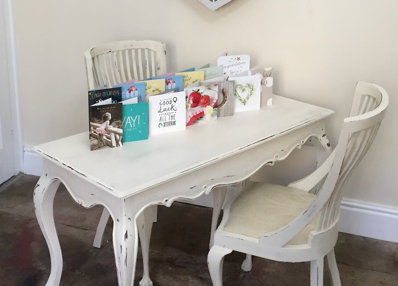 Vintage white table with cards displayed at Azuri, Ripon, England, GB, showcasing stylish ambiance.