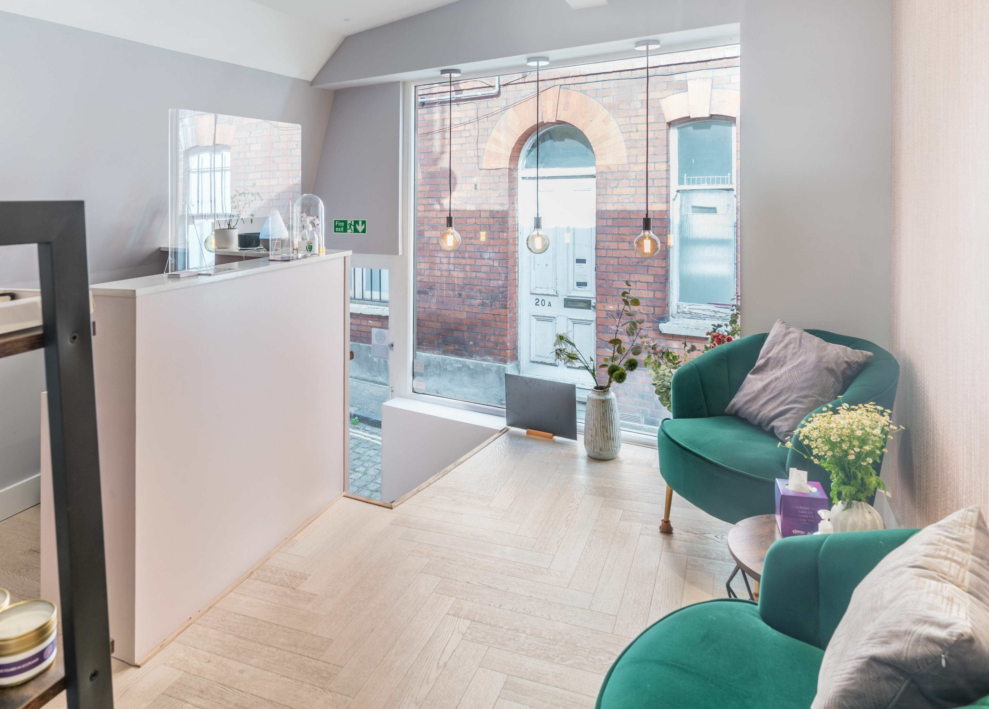 Elegant reception area at Walking on Clouds in London, England, GB with green chairs and large window.