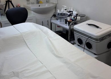 Spa treatment room at MBeauty, Dublin, County Dublin, IE with bed and skincare products on the counter.