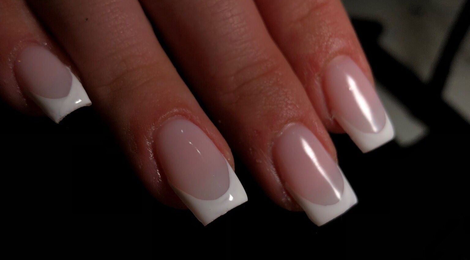 Elegant French manicure at A K Beauty in Kempston, England, GB showcasing glossy white-tipped nails.