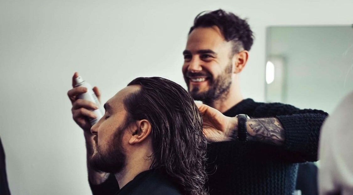 Stylist at Hair by Luigi in Cambridge, England, GB applying hair spray to a client.