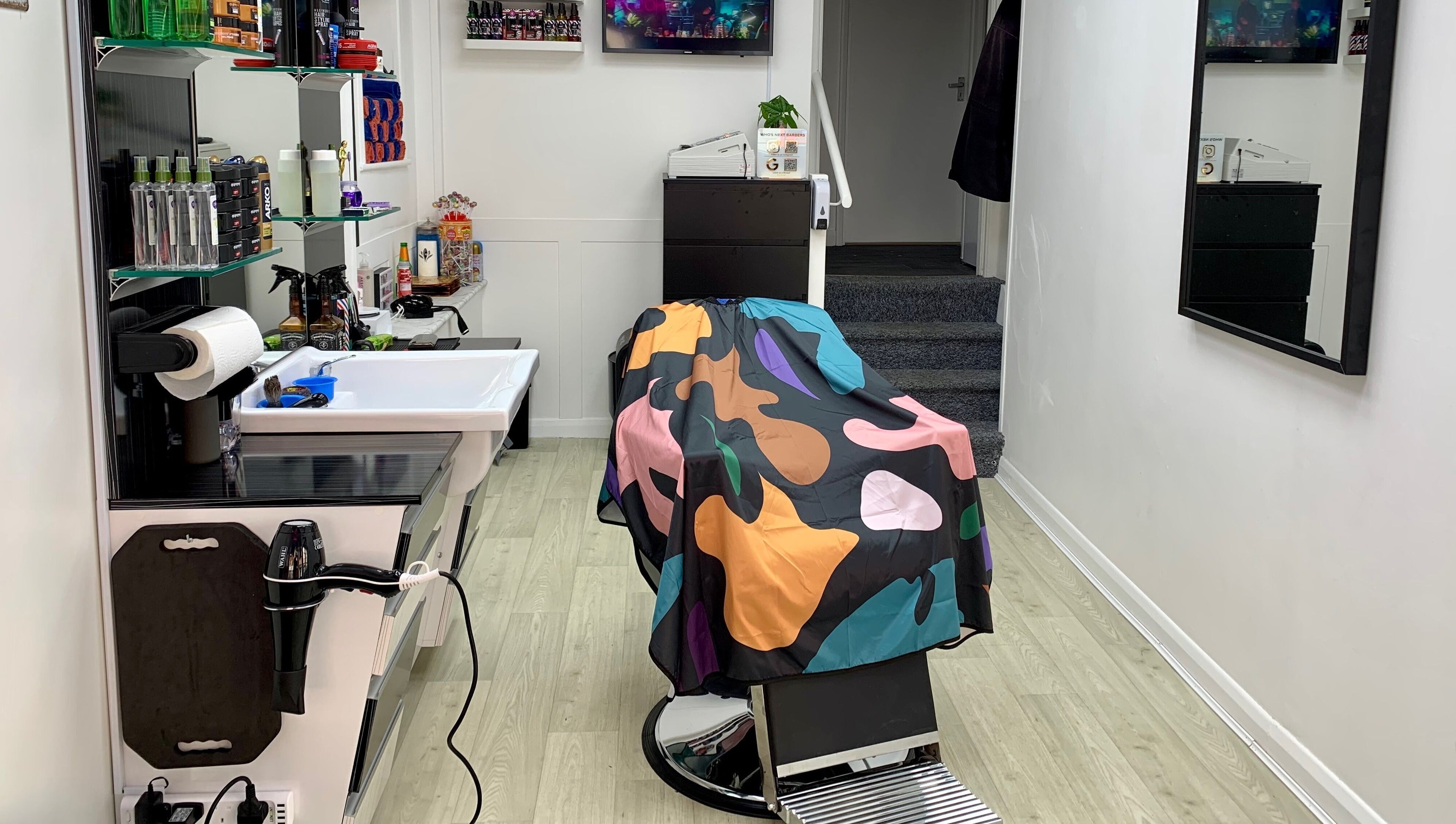 Modern barber chair with colorful cape at Who's Next Barbers, Littlehampton, England, GB.