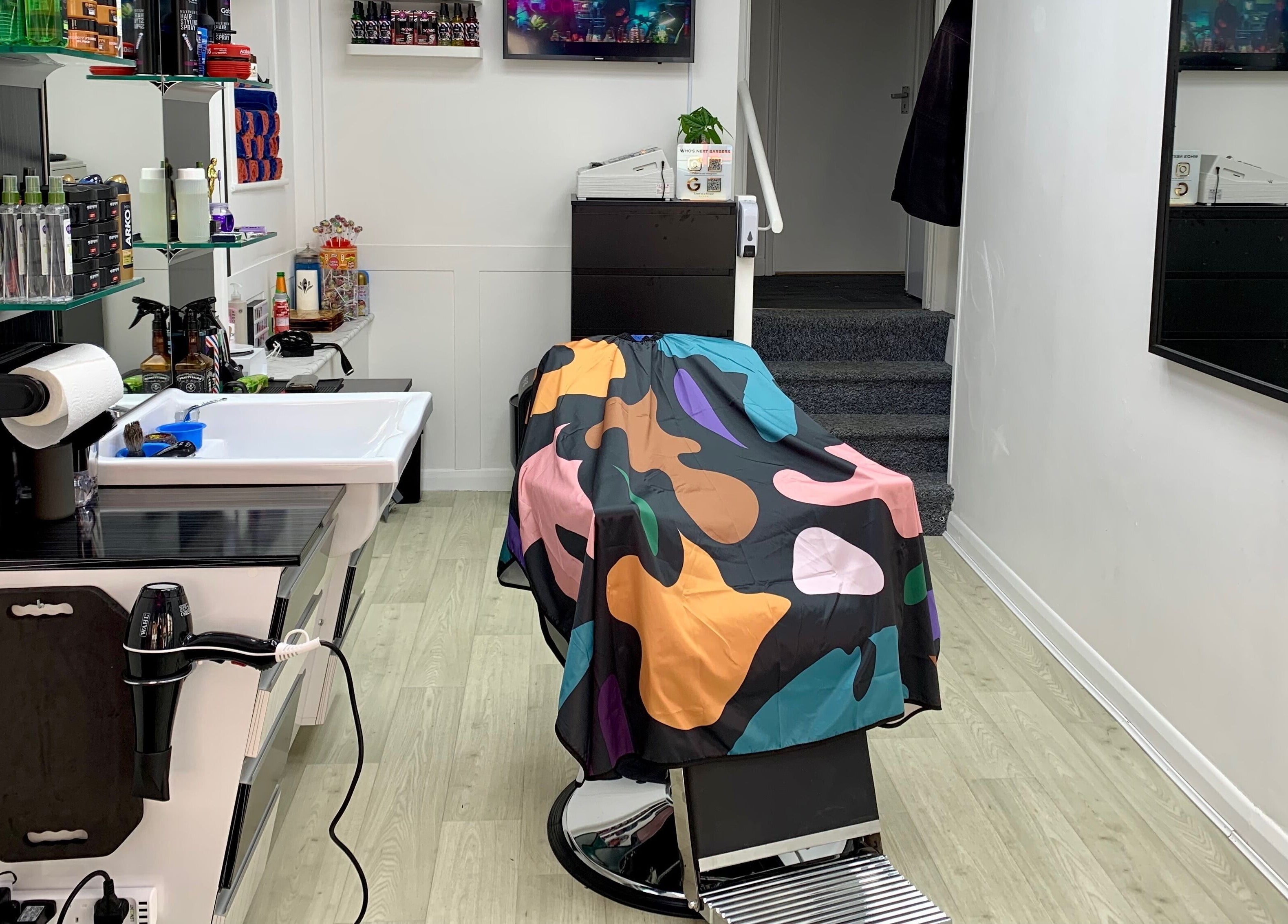 Modern barber chair with colorful cape at Who's Next Barbers, Littlehampton, England, GB.