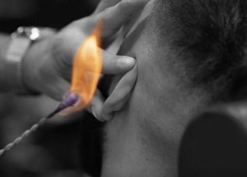 Ear hair removal with flame at Who’s Next Barbers, Littlehampton, England, GB.