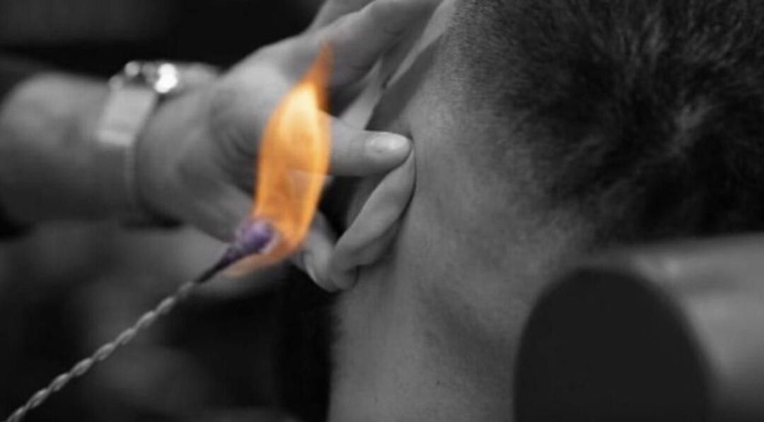 Ear hair removal with flame at Who’s Next Barbers, Littlehampton, England, GB.