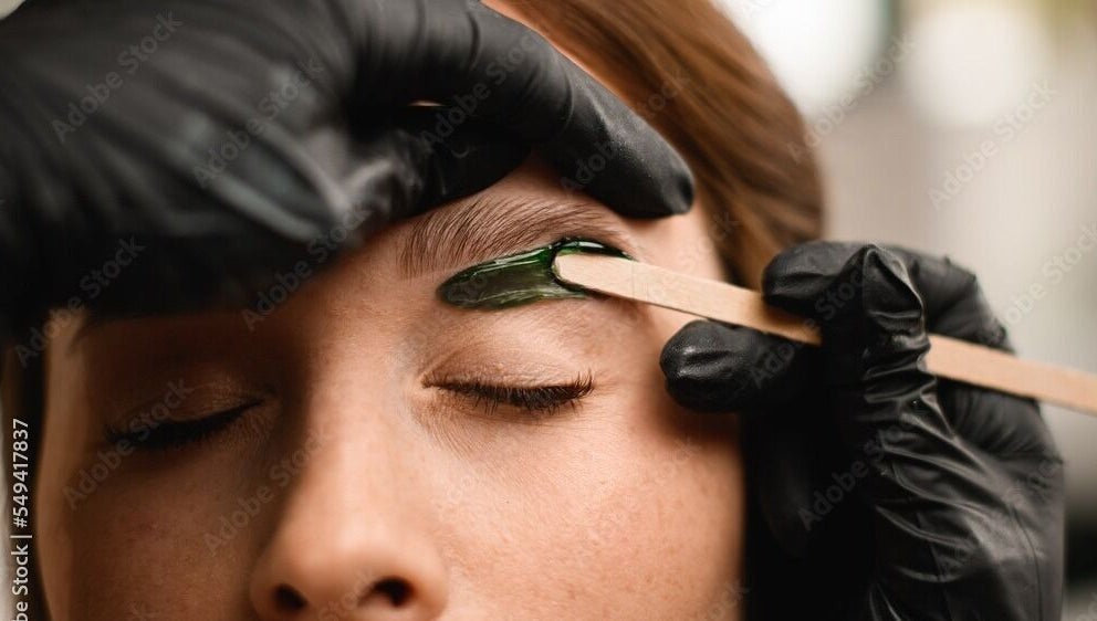 Eyebrow waxing at Chain Lake, Halifax, Nova Scotia, CA. A beautician precisely shapes an eyebrow.