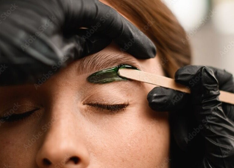 Eyebrow waxing at Chain Lake, Halifax, Nova Scotia, CA. A beautician precisely shapes an eyebrow.