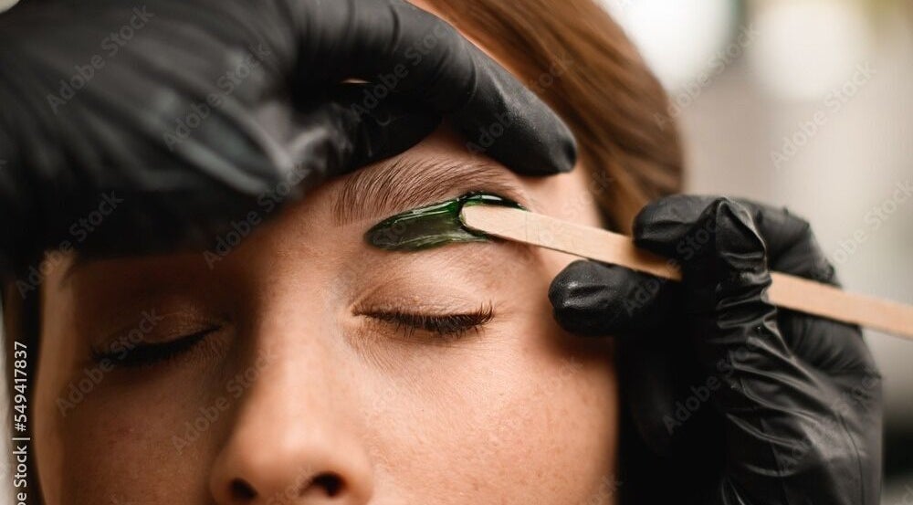 Eyebrow waxing at Chain Lake, Halifax, Nova Scotia, CA. A beautician precisely shapes an eyebrow.