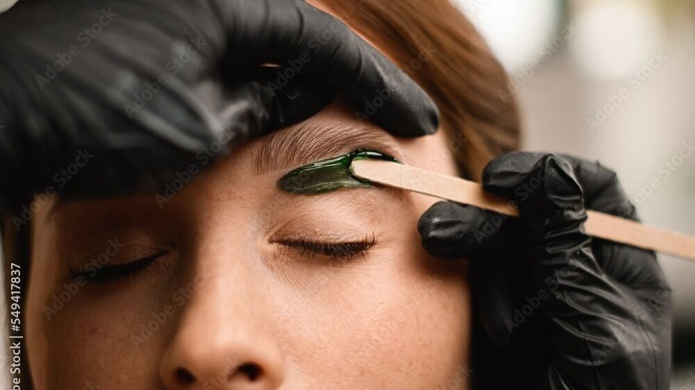 Eyebrow waxing at Chain Lake, Halifax, Nova Scotia, CA. A beautician precisely shapes an eyebrow.