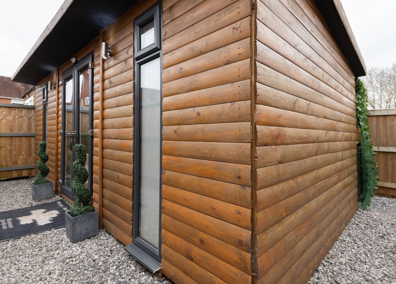 Entrance of The Aesthetics Bae Clinic - Winchester with wooden facade and modern plants, Winchester, England, GB.