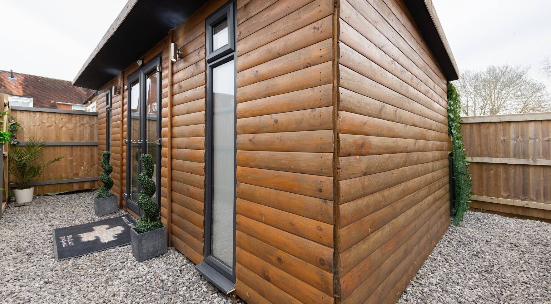 Entrance of The Aesthetics Bae Clinic - Winchester with wooden facade and modern plants, Winchester, England, GB.