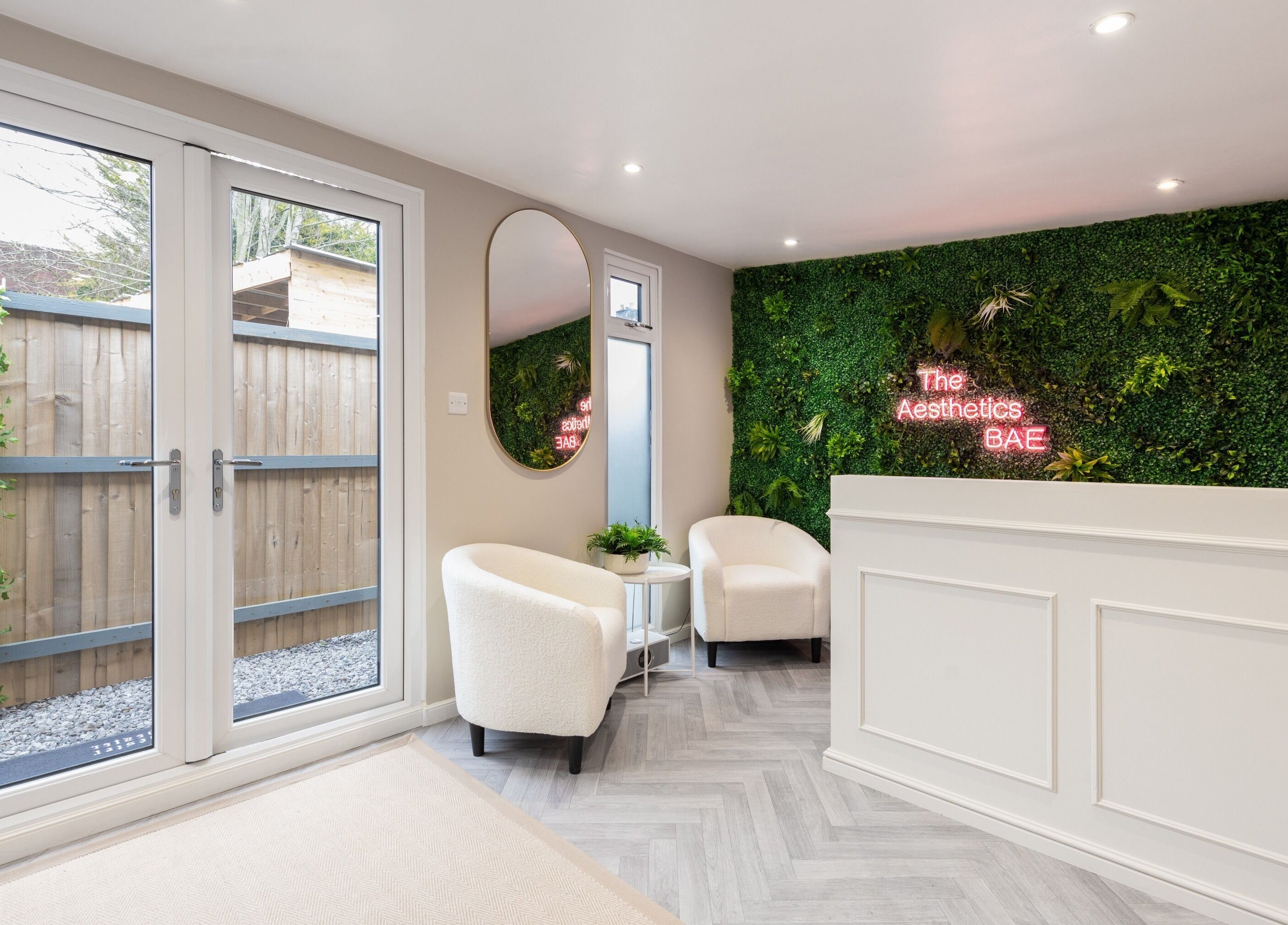 Reception area of The Aesthetics Bae Clinic - Winchester, showcasing lush green wall and modern décor in Winchester, England, GB.