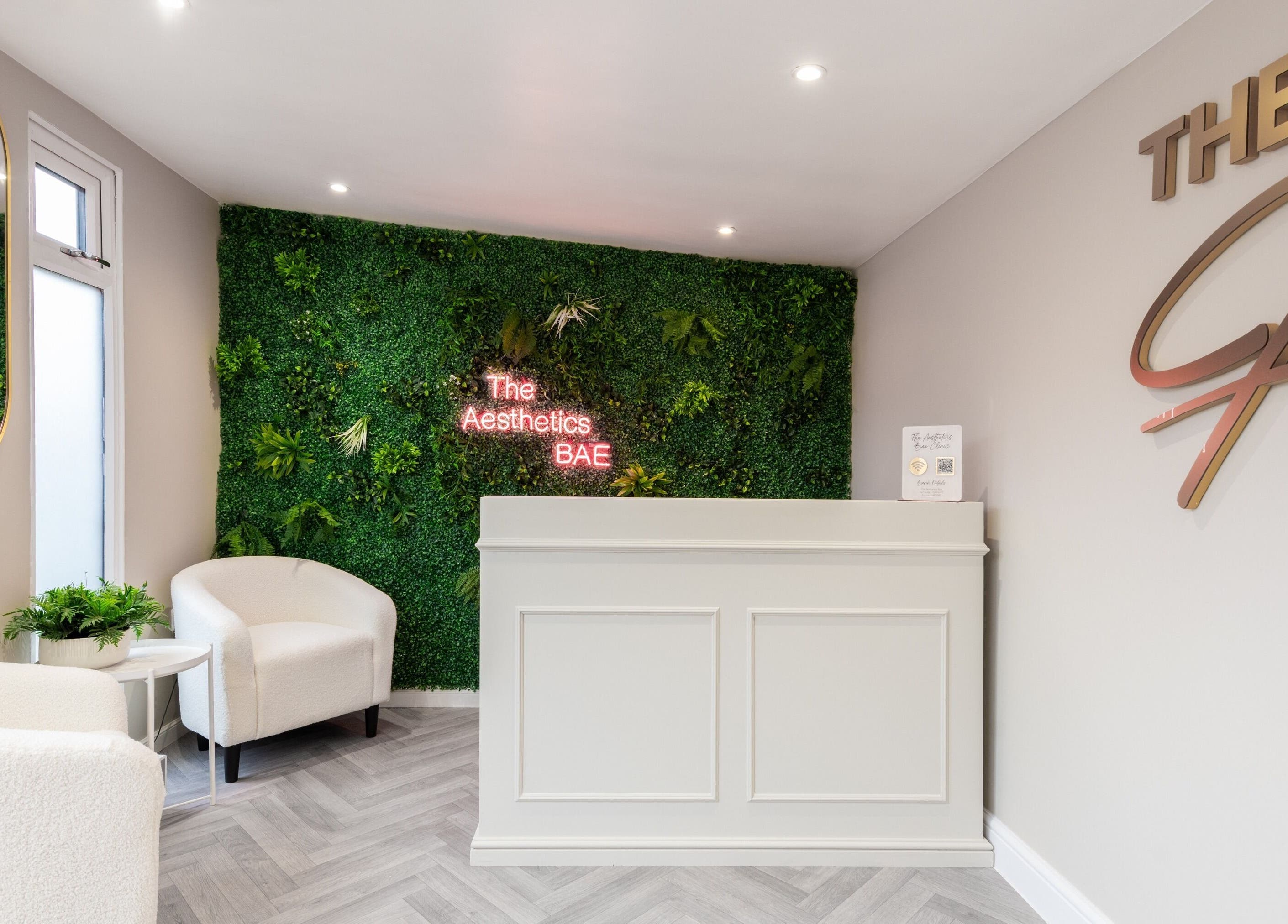 Reception area at The Aesthetics Bae Clinic - Winchester featuring lush green wall, cozy chairs, Winchester, England, GB.