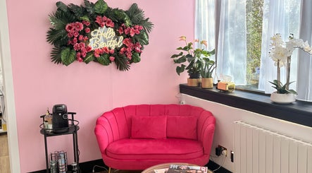 Chic pink lounge at Bare Beauty Stafford, England with floral decor and window lighting.