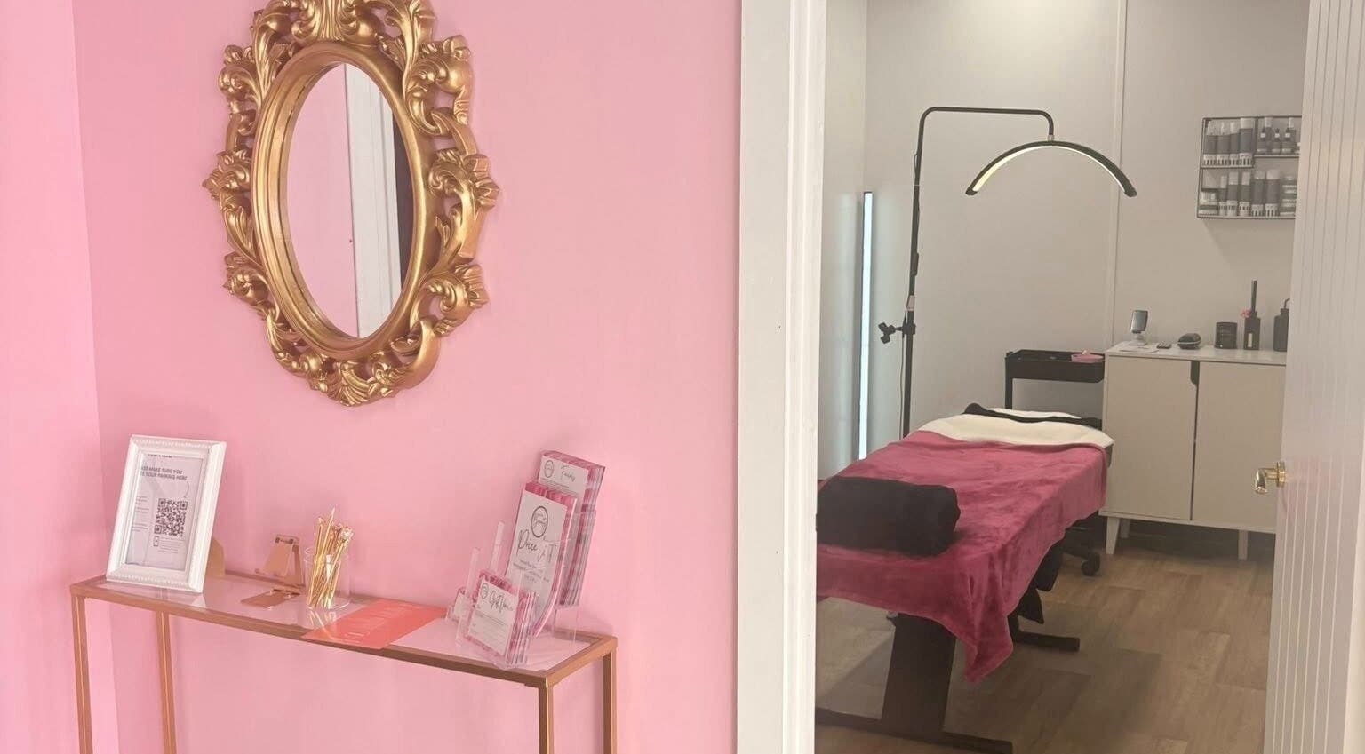 Elegant pink treatment room at Bare Beauty, Stafford, England, GB with ornate mirror and therapy bed.