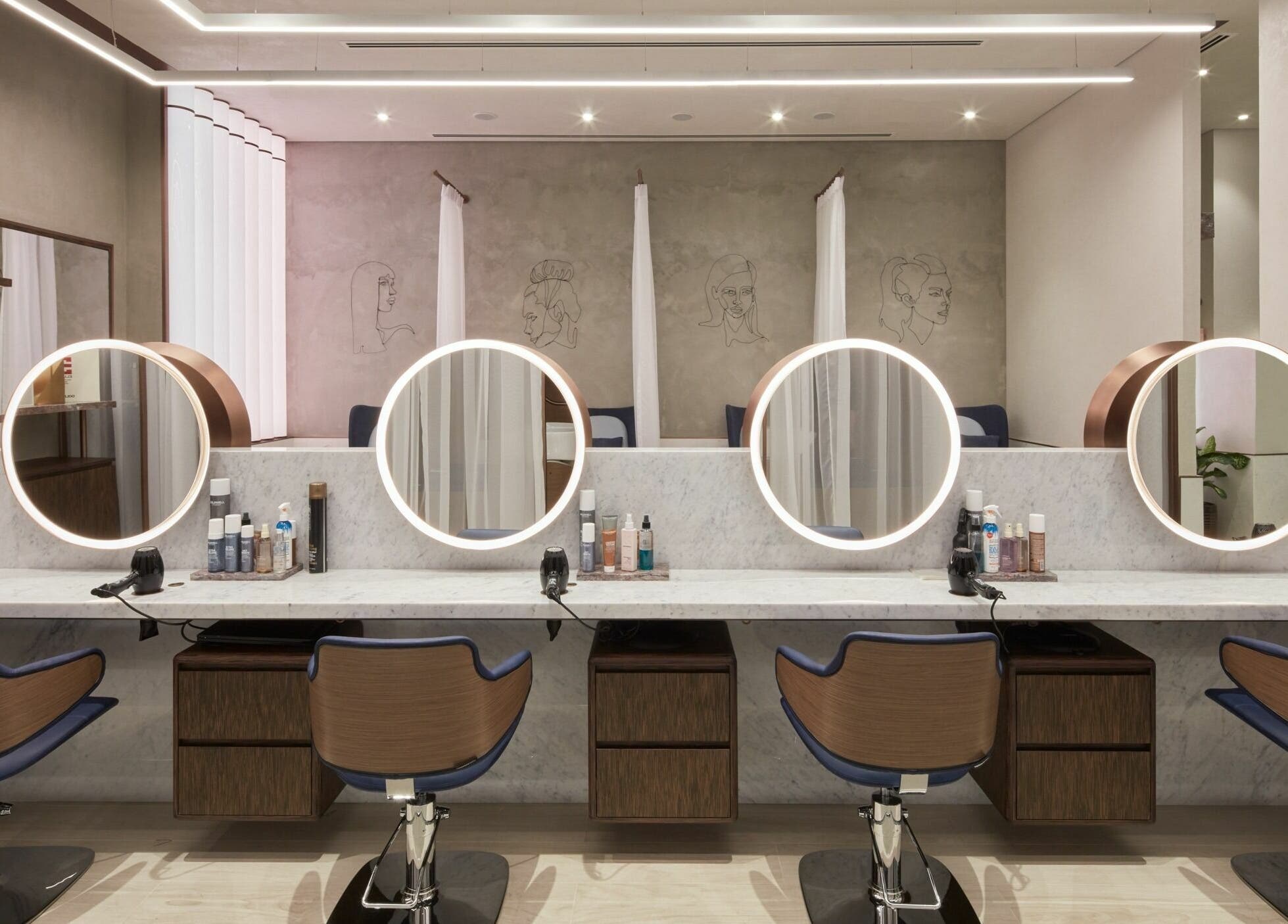 Elegant salon space at Rose Poudre Beauty Bar with modern mirrors and styling chairs in Abu Dhabi, AE.