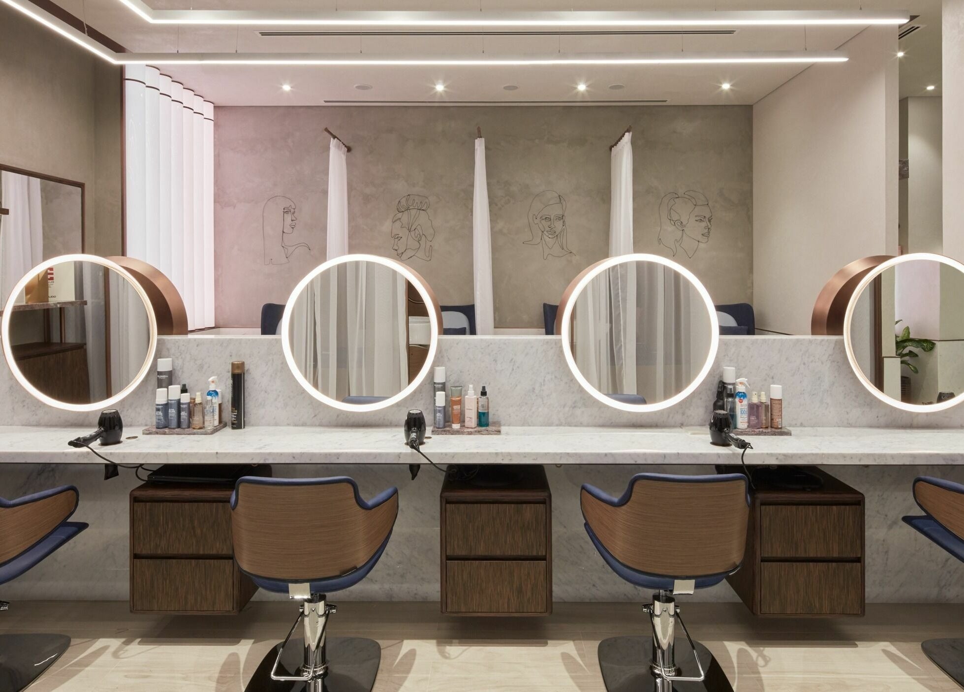 Elegant salon space at Rose Poudre Beauty Bar with modern mirrors and styling chairs in Abu Dhabi, AE.